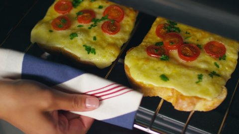 Close-up of pulling melted cheese toast out of the oven.