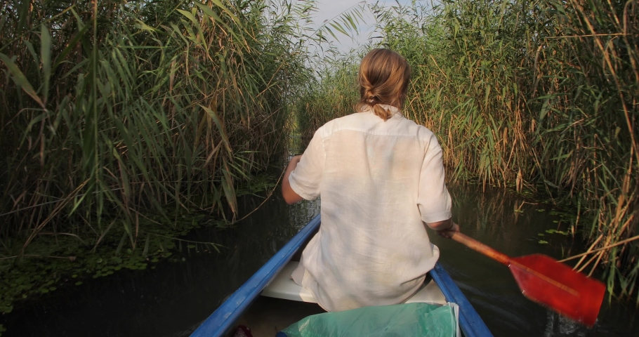 Canoeing in wild natural environment, narrow passage in the reed