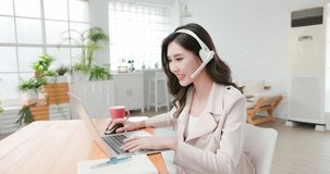 telework concept - Asian woman use computer and headphone microphone to join a video meeting at home