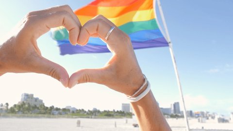 Hands making heart with hands on gay rainbow flag, Miami Beach, Lgbt concept, Miami Beach -slow motion