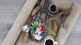 Cup of black coffee with pot and dried logs on wooden table background.