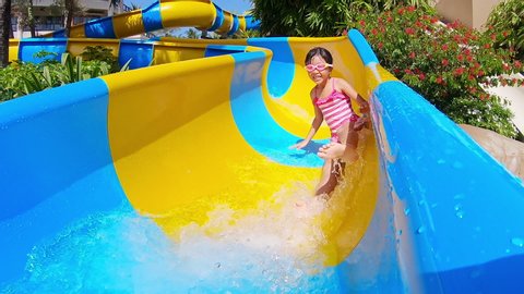slow motion of asian girl enjoys water slide ride in aquapark
