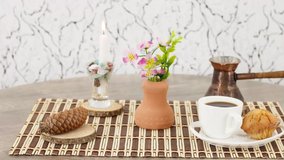 Cup of black coffee with pot and candle on wooden table background.