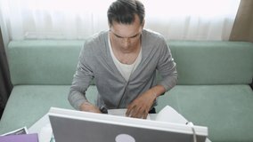Young man working from home, working at a computer and checks documents, quarantine, home office.