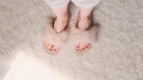 Female feet in fluffy pink slippers dancing toes. Cozy house, stay home.