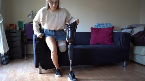 Young woman putting on her artificial leg at home