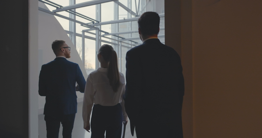 Young male real estate agent showing spacious empty accommodation with glass ceiling and walls to couple of business people. Entrepreneurs rent office for new business Royalty-Free Stock Footage #1051746037