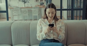 Happy Woman with smartphone at home, Female sitting on couch in living room. Online shopping,Technology, Communication. 4K slow motion video.
