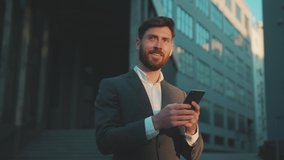 Shot move around businessman stand in the city center street uses phone texting scrolling tapping smile technology communication sunny day success slow motion - Powered by Shutterstock - Get 15% off with code: PIKWIZARD15