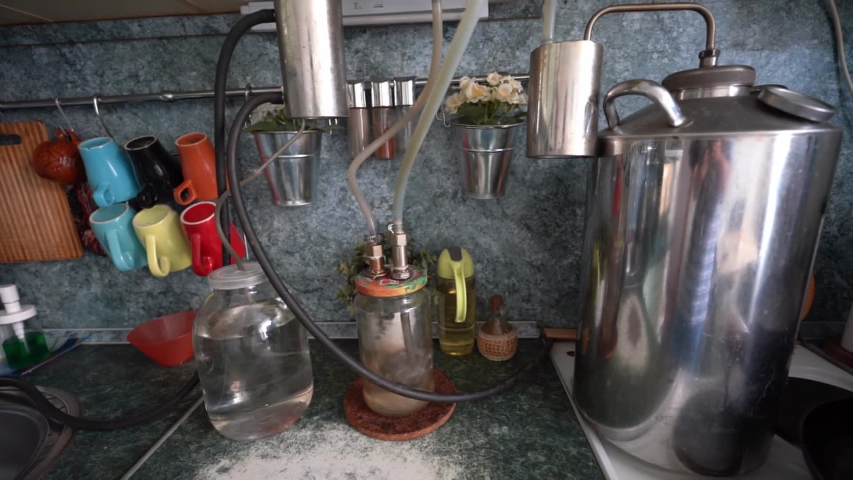 A homemade apparatus for the production of moonshine at home in the kitchen. Large saucepan and a tube is inserted into the banks, the bubbles in the liquid