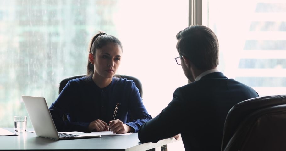 Confident young businesswoman sitting at table, holding negotiation meeting with male partner, discussing project ideas details together. Skilled female hr manager interviewing job seeker applicant. Royalty-Free Stock Footage #1051758079