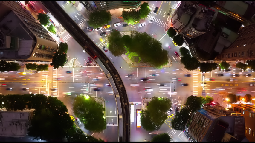 Top down Hyper-lapse of the busy traffic dashing thru the circular intersection of Heping and Keelung Roads in Taipei City at night and metro trains traveling on elevated Wenhu Line across the rotary Royalty-Free Stock Footage #1051759744