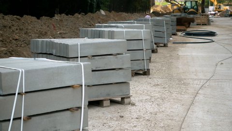 Curb stone for road construction. Concrete blocks on a wooden pallet at a construction site. HD