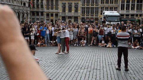 Belgium/Brussels 2019-07-07 slow motion street attraction in Belgium Brussels artist jumping over girls successfully parkour danger extreme flip in the air over people.