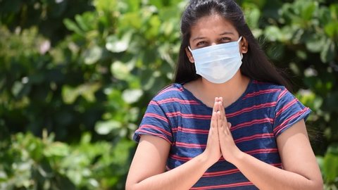 Indian woman wearing medical mask saying no to Handshake and instructing to do Namaste to maintain social distance during the Coronavirus pandemic