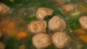 Homemade vegetable soup with meatballs in a pan. Spinach. Close-up.