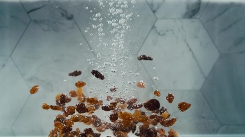 Raisins dropping into water in slow motion
