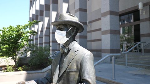 Raleigh, NC / USA - May 2 2020: A statue of NC Museum of History founder Frederick Olds wears a white cloth mask during the COVID-19 pandemic
