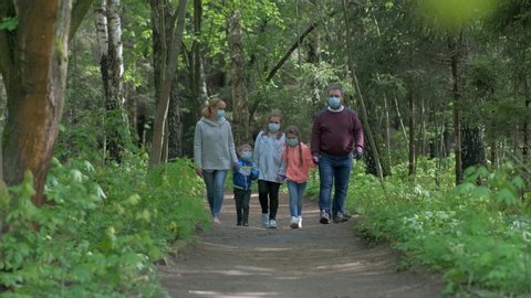 Family: father, mother, son and two daughters walk in the Park in medical masks in the spring. The concept of protection FROM covid-19 coronavirus infections.