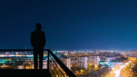 The man standing on the top of building on the night cityscape background