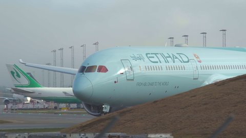 oslo airport norway - ca may 2020: airplane etihad airways boeing 787 greenliner taxiing turning appear behind obstacle sunny morning