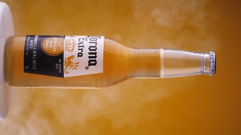 MINSK, BELARUS, May 4, 2020: Bottle of Corona Extra beer on yellow background, one of the top-selling beers worldwide is a pale lager produced by Cerveceria Modelo in Mexico. Vertical shot.