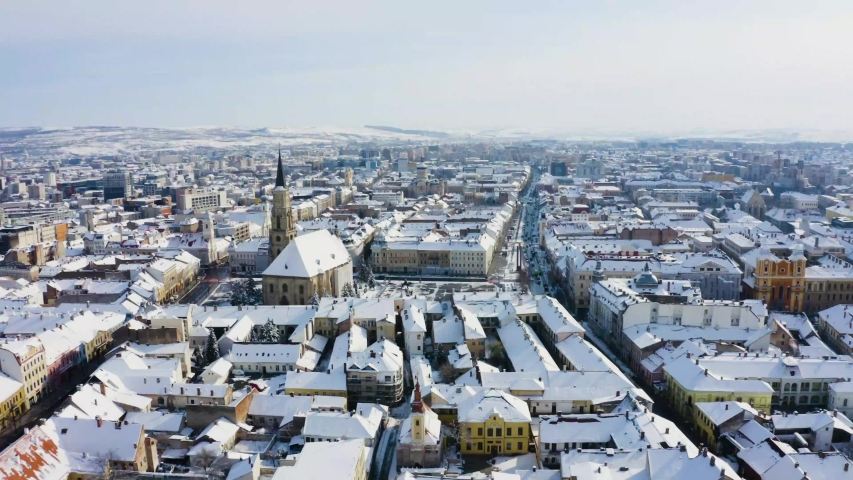 Aerial shot over the main square and church in Cluj, Romania, covered in snow. Empty streets during coronavirus lockdown