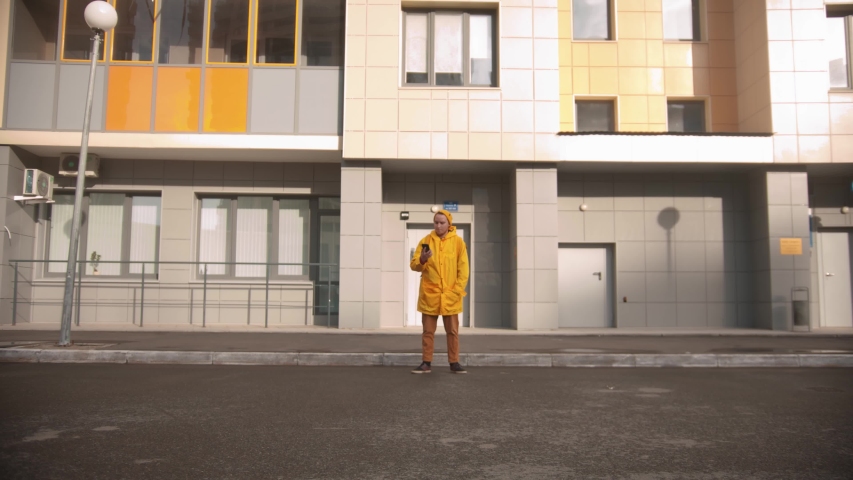 Man courier in yellow clothes delivers food - looking around and walks in the porch