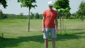 Funny man is dancing in the park in a virtual reality helmet. Guy in a red T-shirt and blue shorts repeats movements in VR glasses. 4K footage