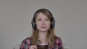 Close-up portrait of charming Caucasian blond woman drinking coffee during online conference. Young employee having break on video chat. Covid-19 lockdown lifestyle, isolation, wireless communication.