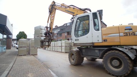 Schimmert, The Netherlands - August 3, 2017 - Excavator Putting Down Filled Pallet Inside Of A Village