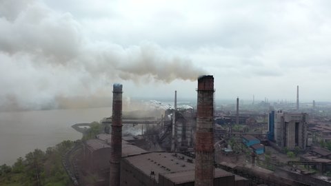 huge pipes emit white and red smoke into atmosphere, heavy industry, metallurgy, chemical plants. huge area with old factories. pollution of environment, rivers and air. smog and smoke Industrial city