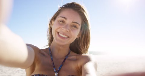 beautiful young Brazilian woman taking selfie on beach at sunset