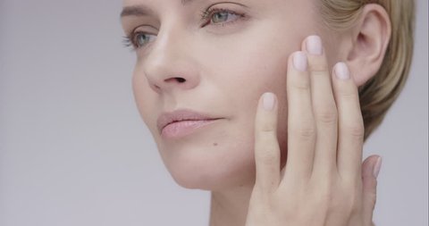 Close up of Beautiful healthy woman touching smooth skin on face in slow motion for beauty skincare concept on a grey background Shot in 6K on RED EPIC DRAGON