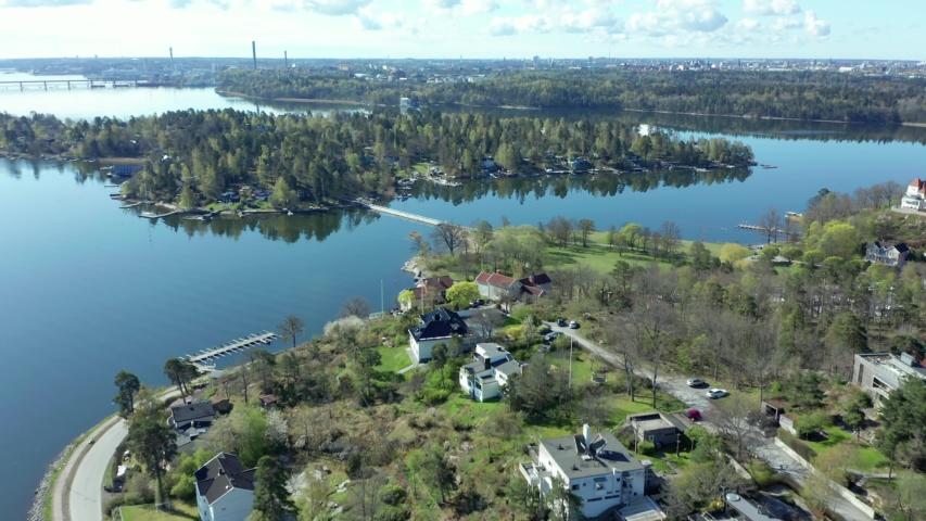 Drone shot of Djursholm Stockholm suburban in Danderyd Municipality, wealthiest community in Sweden. Aerial of luxury estate, fancy mansions, big houses with gardens. City center background at horizon Royalty-Free Stock Footage #1051817140