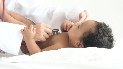 Close-up shot of pediatrician examines african baby boy. Doctor using a stethoscope to listen to baby's chest checking heart beat.Concept health , lung disease , corona virus covid19.