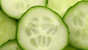 Sliced pieces of green cucumber stacked on a hill rotate, top view, spinning slowly in a circle, close up.