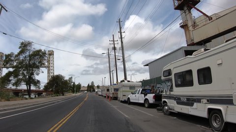 Oakland, CA - May 2, 2020: 4K HD video driving POV down Alameda Ave in Oakland near HomeDepot, dozens of trailers, cars and tents along road. Homeless encampment.