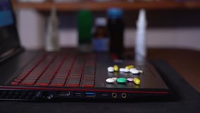 On the surface of the laptop move colored tablets in a pile. blurred background. close-up. 4K resolution