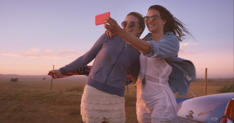 beautiful Girl friends taking selfies on road trip at sunset with vintage car RED DRAGON