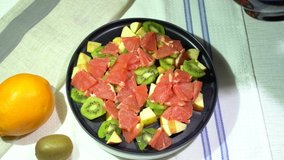 Preparing fruit salad with orange fruit, mango, kiwi and apple. Adding mango pieces. A part of. Step by step.