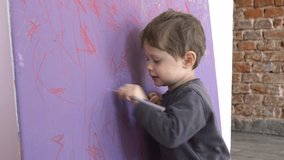 Little toddler boy is draws on the wall at home