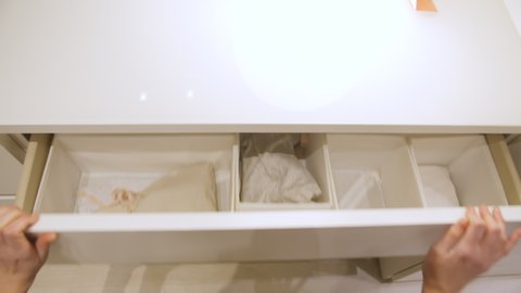 Pov shot of female hands opening drawer in closet and choosing underwear. Woman taking clothes from drawer with underwear and bedding clothes in closet.