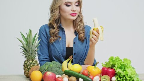 Healthy food at home, woman in the kitchen eating a ripe banana