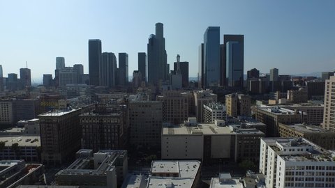 Aerial shot pulling back from downtown Los Angeles skyline on sunny day with clear skies in 4K