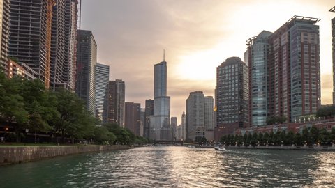 Chicago, IL - June 28th, 2018: Recreational vessels, speed boats and tour boats cruise down the river during sunset as the sky turns from orange to pink near the Trump International Hotel and Tower.