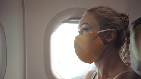Woman travel caucasian at plane with wearing protective medical mask. Girl tourist at aircraft with protect respirator. Concept virus protection coronavirus epidemic sars-cov-2 covid-19 2019-ncov.