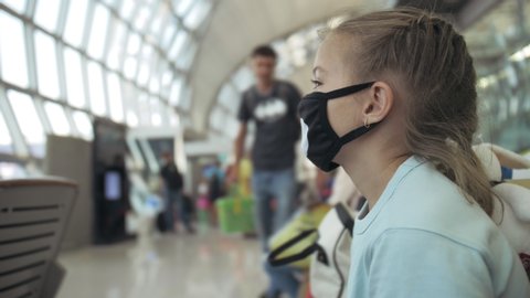 Children girl kid caucasian at airport with wearing protective medical mask on head against background of plane. Concept health virus protection coronavirus epidemic sars-cov-2 covid-19 2019-ncov.