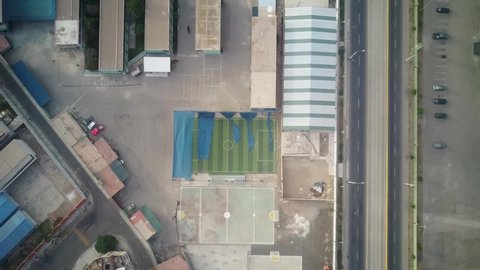 View of the drone going descending on a futsal field with parked cars, public transportation metropolitano, with no people middle of pandemic quarantine lockdown ocean with empty streets. stadium
