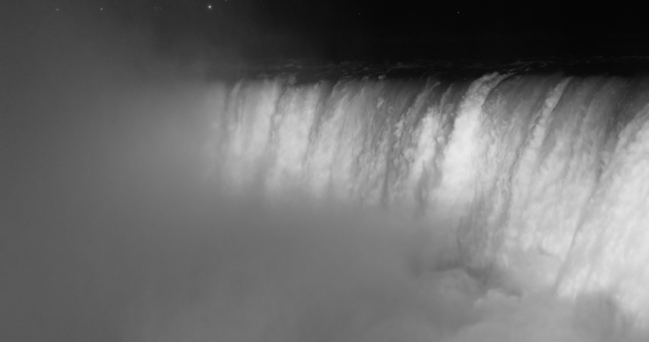 NIAGARA FALLS, NEW YORK - 8 AUG 2019: Niagara Falls bottom at river brink lights flashing waterfalls. International border USA New York and Canadian province Ontario. honeymoon vacation destination.